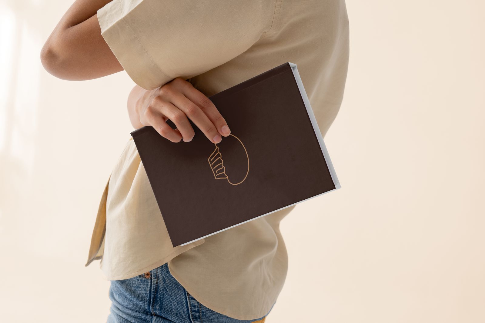 The Muffin Manifesto book held under arm, dark cover with gold muffin icon