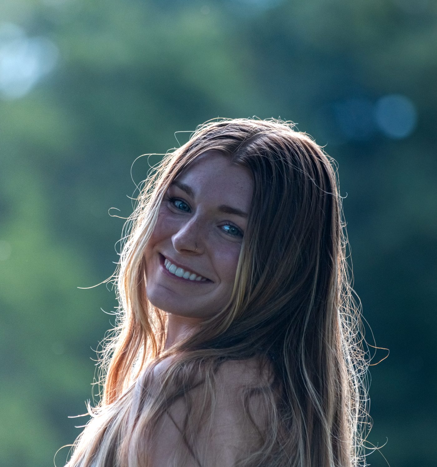 Close-up smiling portrait with sunlit hair against green foliage