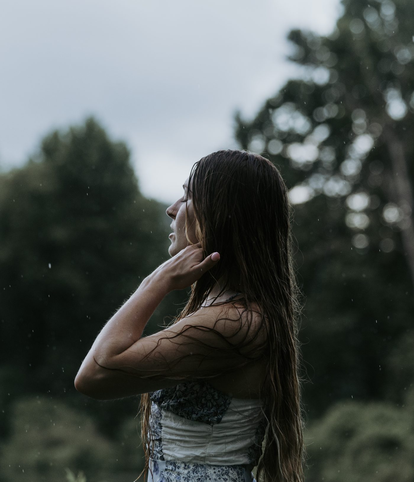 Profile portrait in the rain with eyes closed, hand near the neck