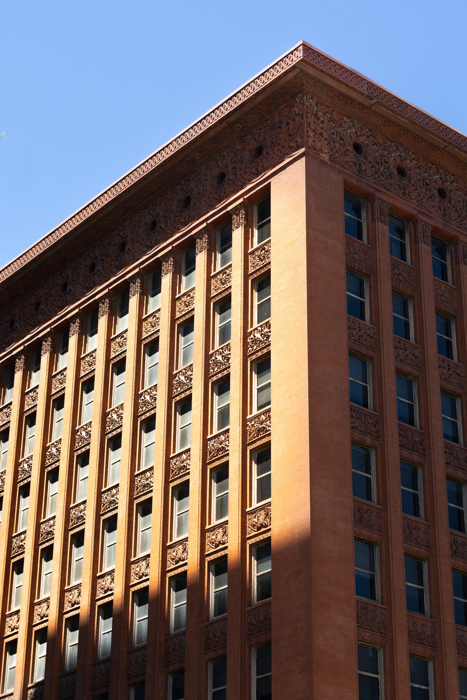 Ornate terracotta building corner with carved cornice, looking up against a blue sky