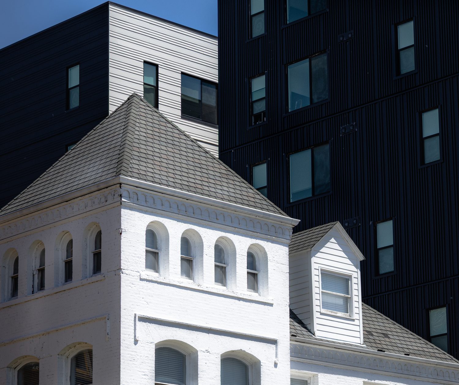 Rooftop dormer of a white Victorian building set against a dark modern high-rise