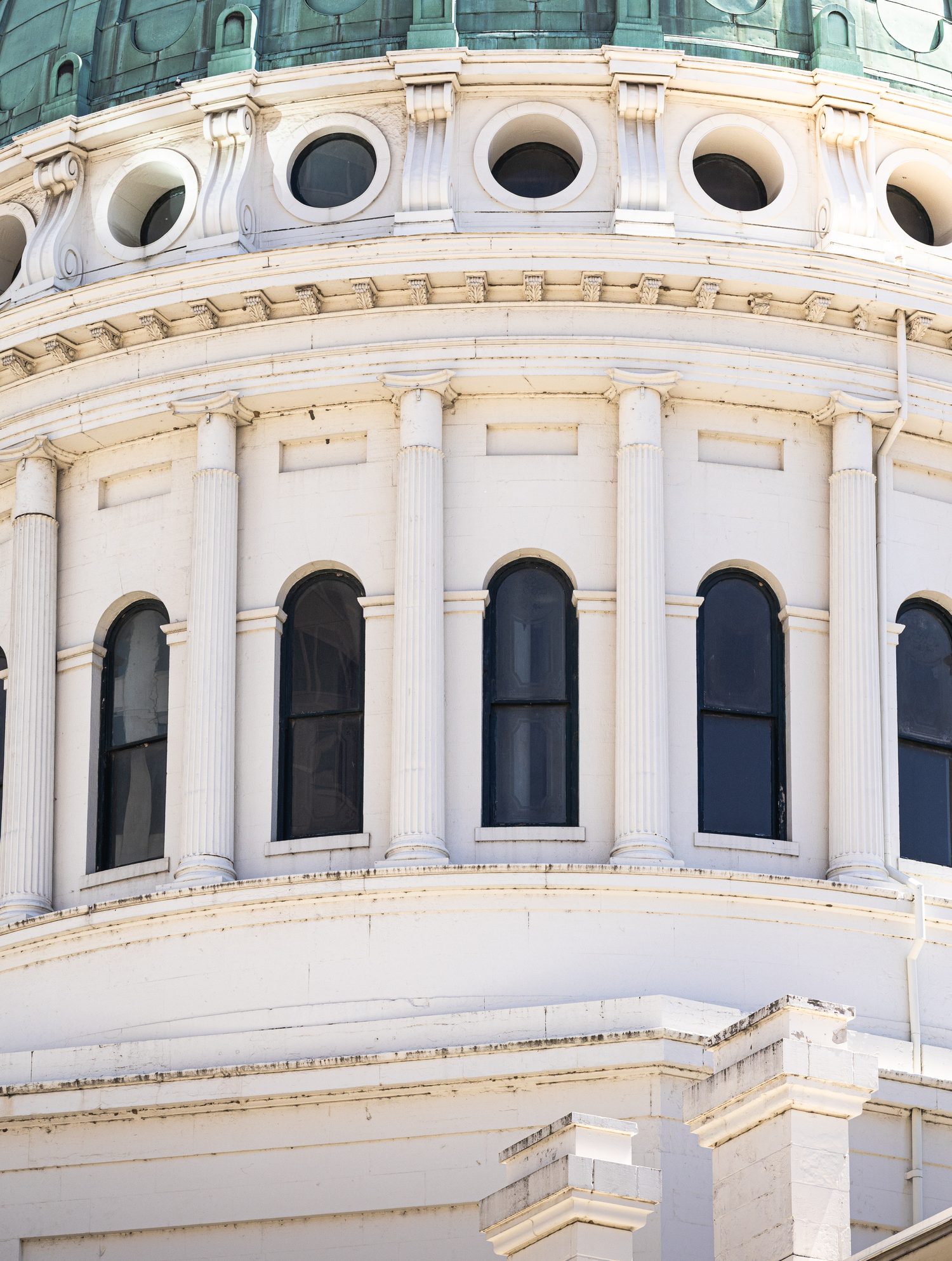 Close-up of a domed rotunda with columns and oculus windows under a copper roof