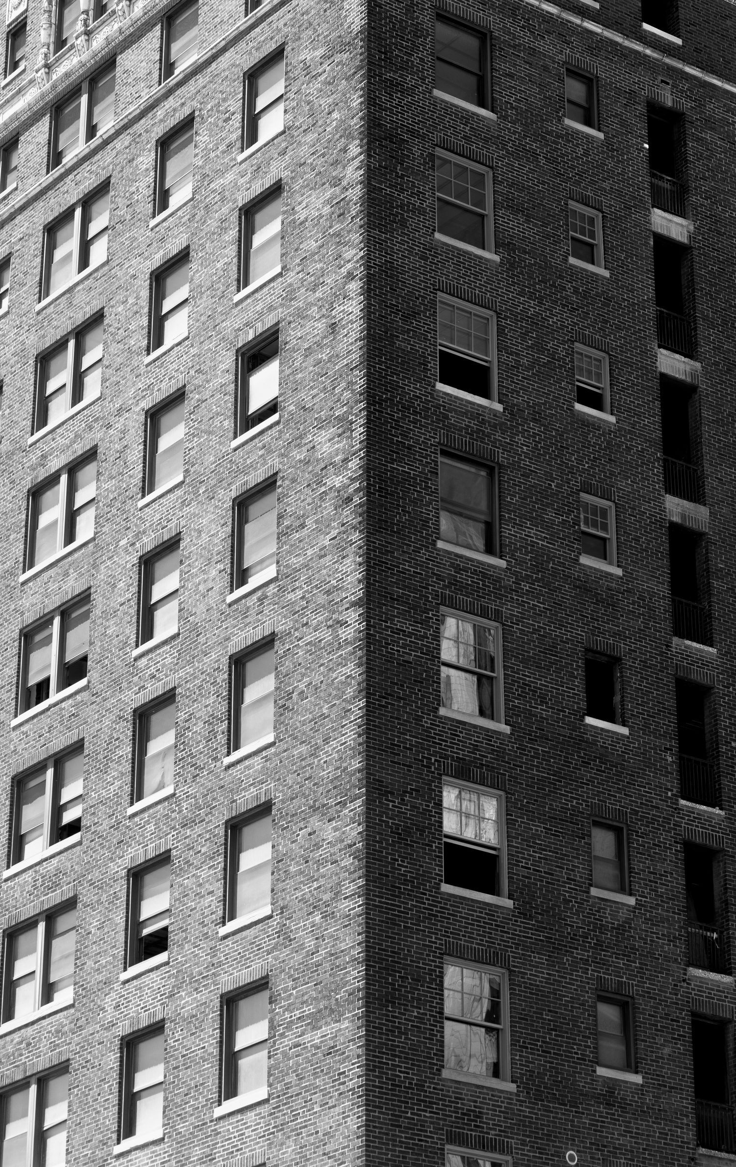 Black and white photo of two brick apartment towers meeting at a corner