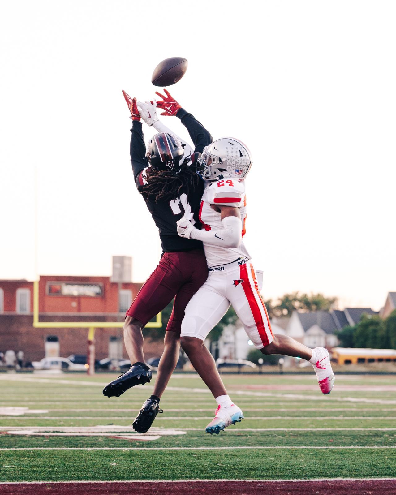 Two players leaping for a pass against a pale evening sky