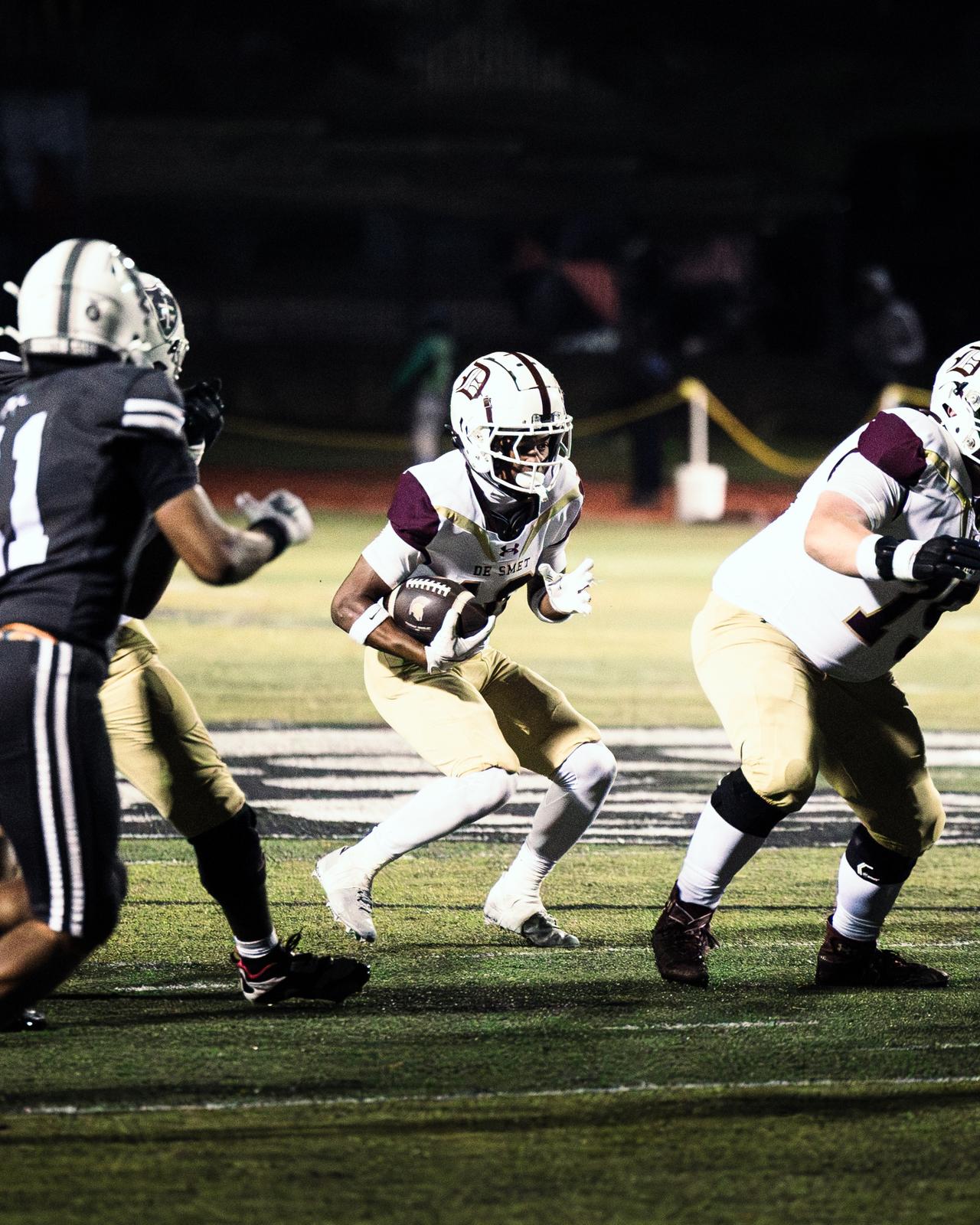 De Smet ball carrier cutting upfield at night with a defender closing in