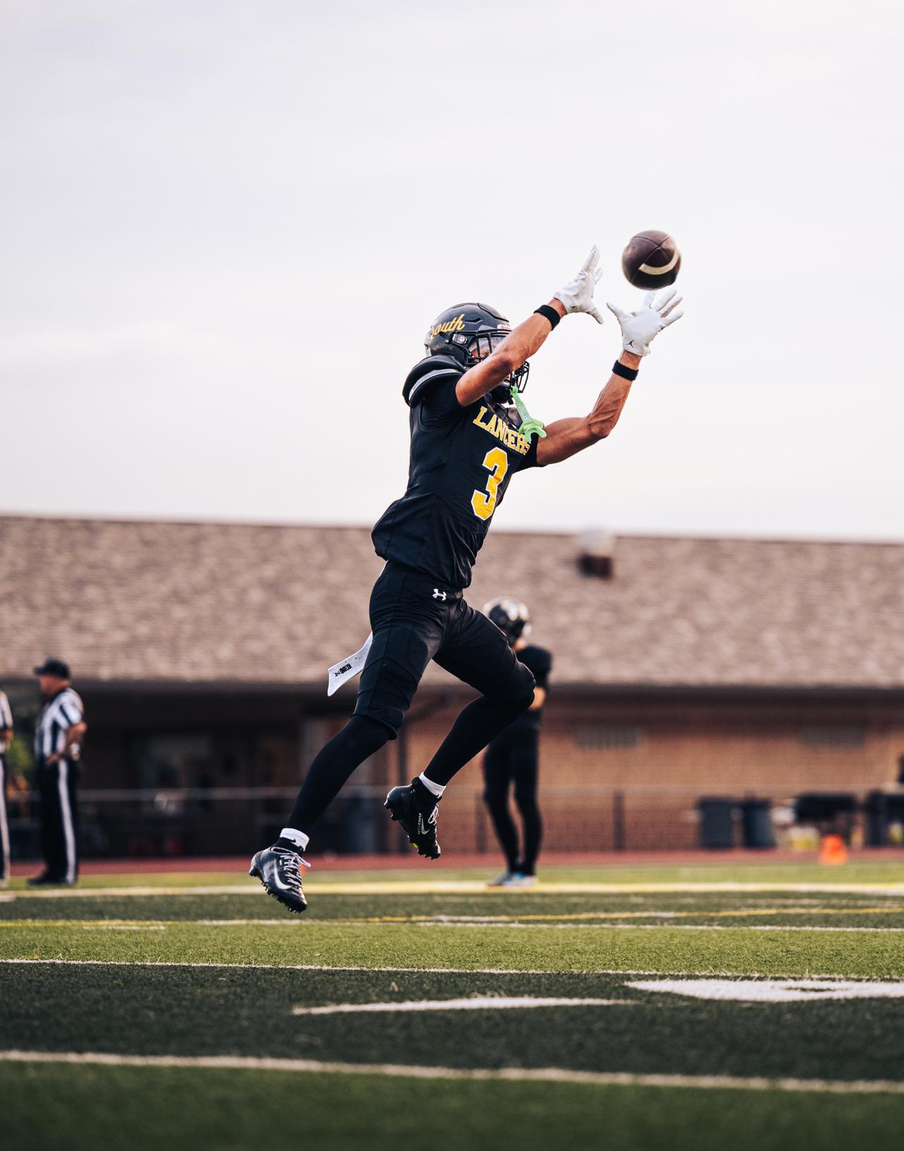 Lancers receiver number 3 leaping to catch a pass against a pale sky