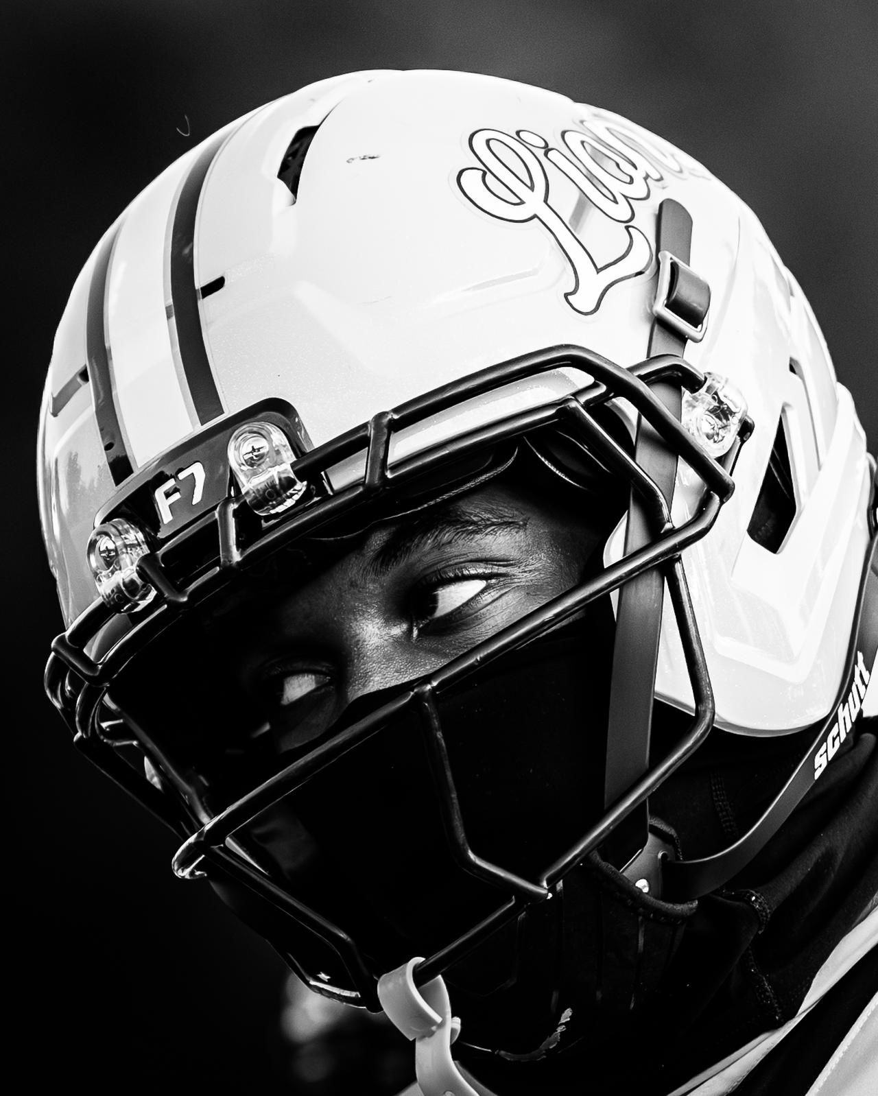 Black and white close-up of a Lions helmet with the player's eyes visible behind the facemask